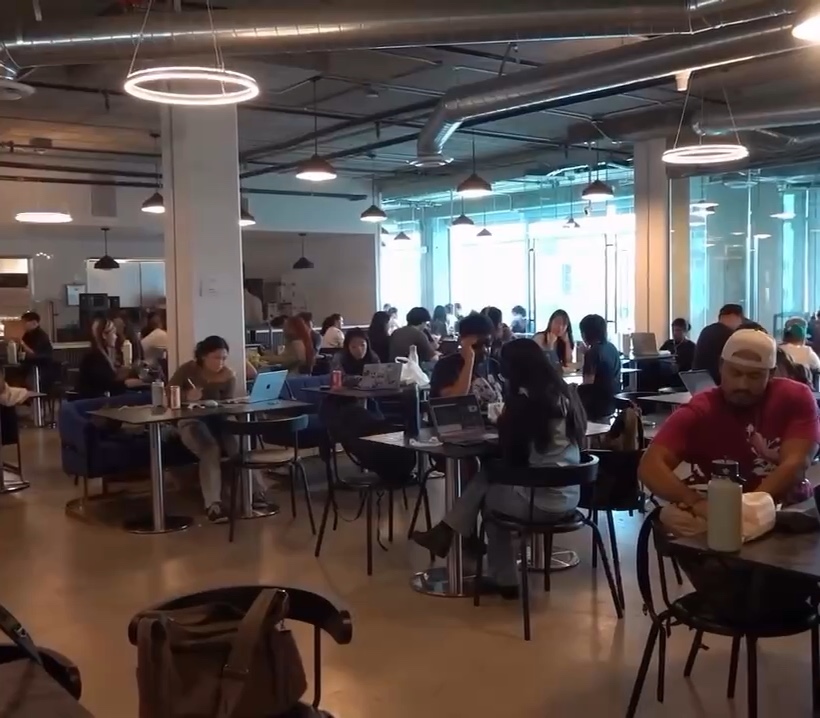 The Motiq dining room in daylight: high ceilings, ring pendant lights, concrete columns and a room full of people at tables.